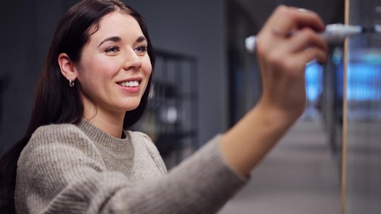 Young woman writing on a whiteboard smiling