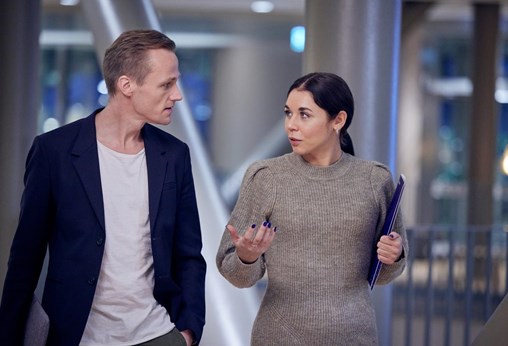 Man and woman walk and talk holding folder