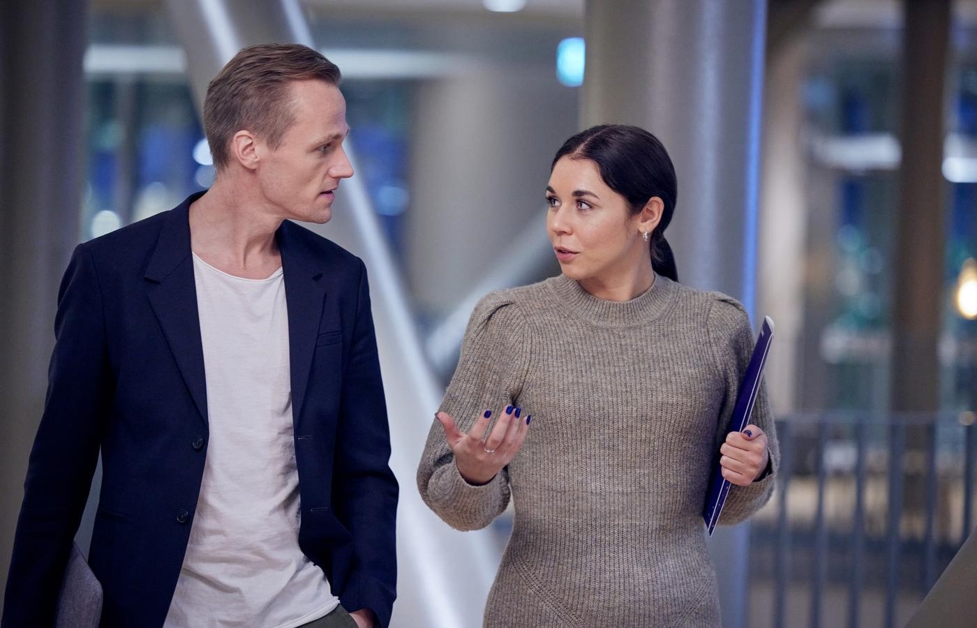 Man and woman walk and talk holding folder